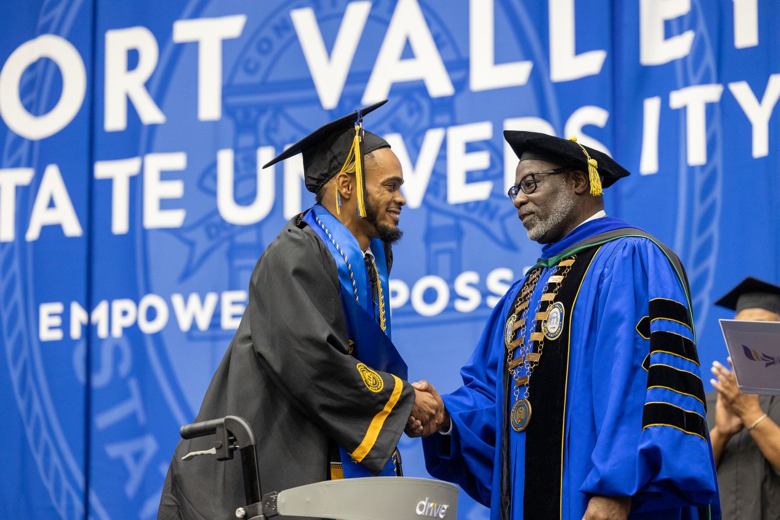 a graduate shakes the hand of the dean at a graduation ceremony