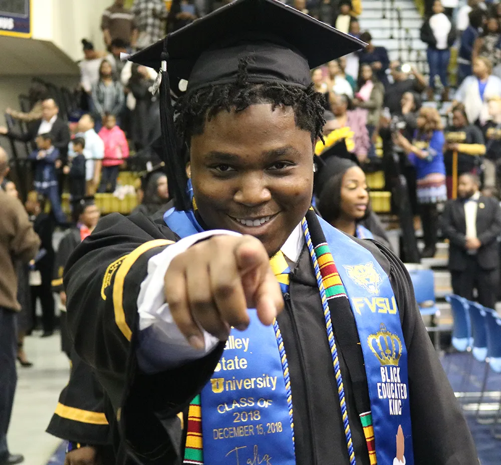 Graduating student pointing to the camera smiling