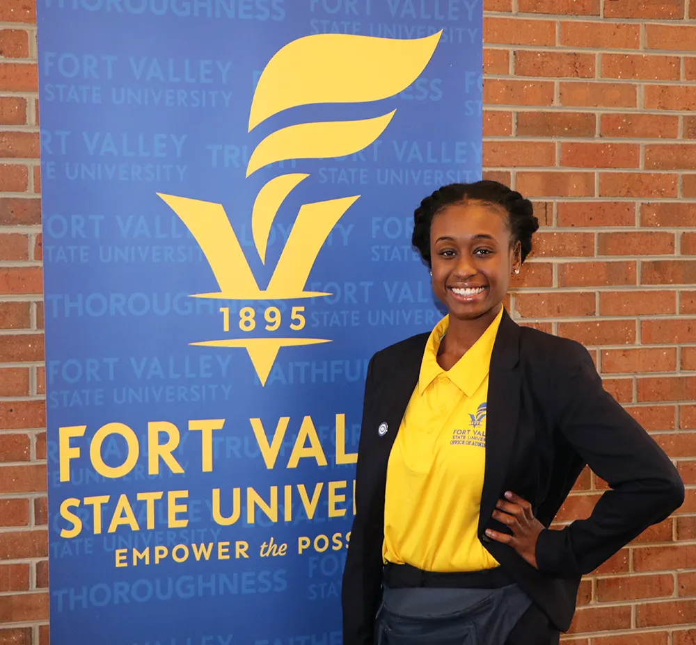 FVSU Advisor posing next to banner